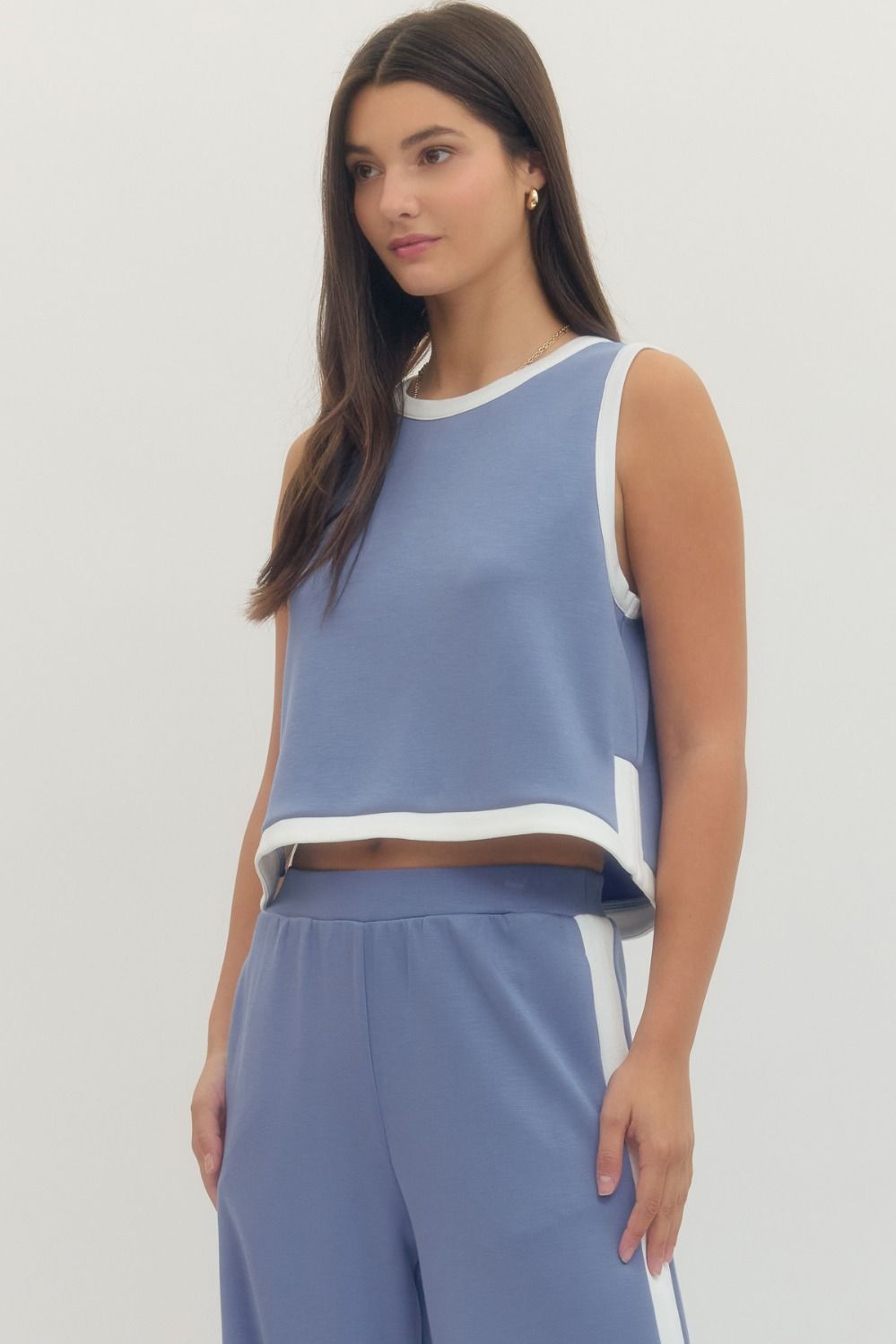 Woman wearing a blue sleeveless top and pants on a white background