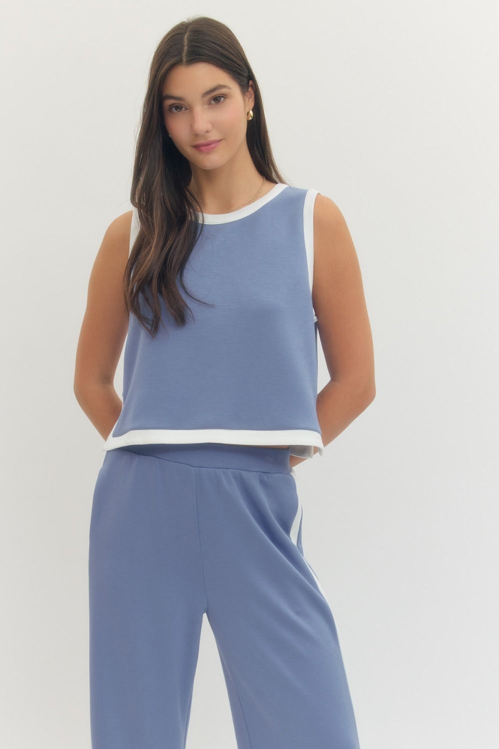 Woman wearing a blue sleeveless top and pants on a white background