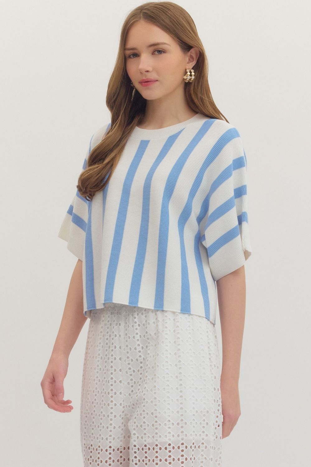 Woman wearing a blue and white striped top with a plain background