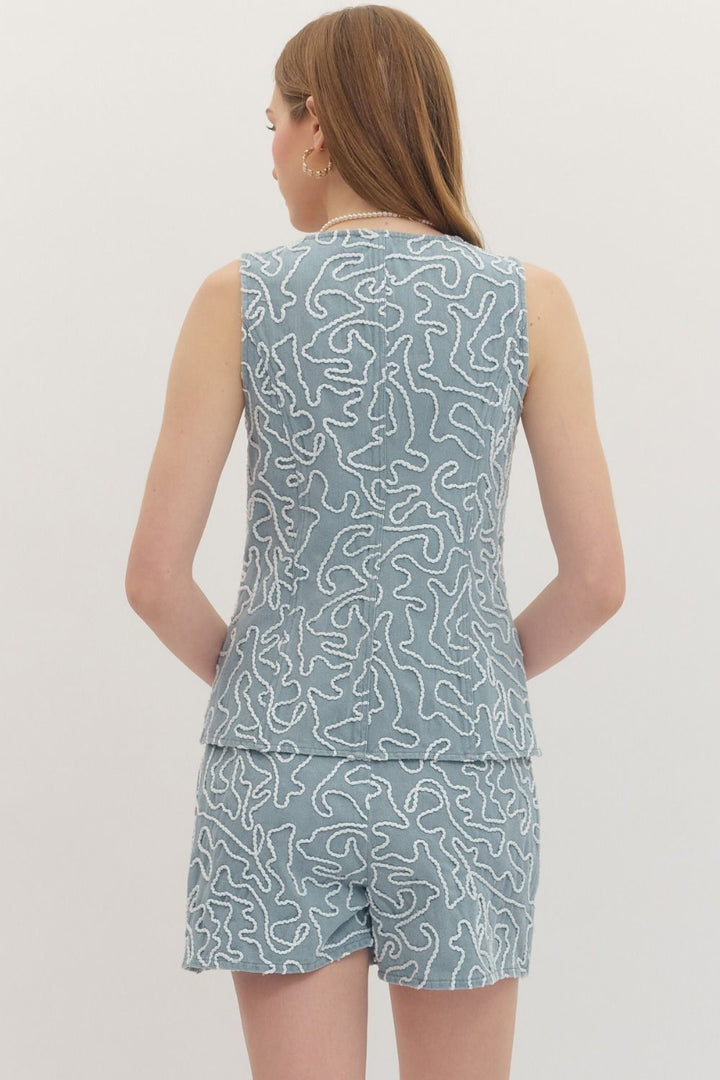 Person wearing a sleeveless top and shorts set with a blue pattern on a plain background