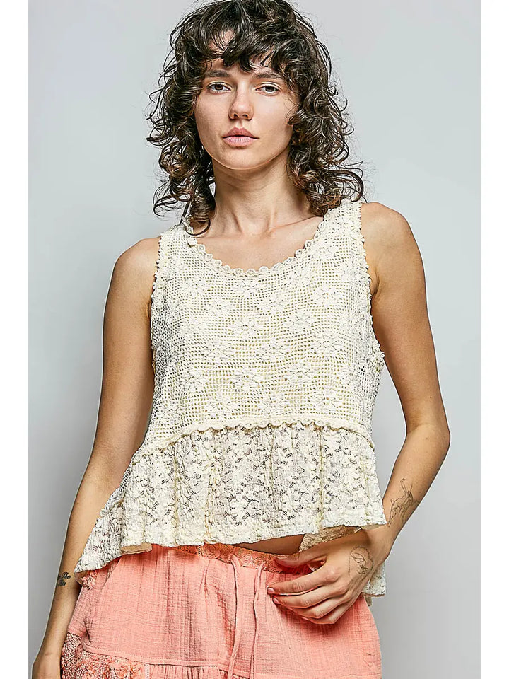 Woman wearing a white lace top and pink pants against a gray background