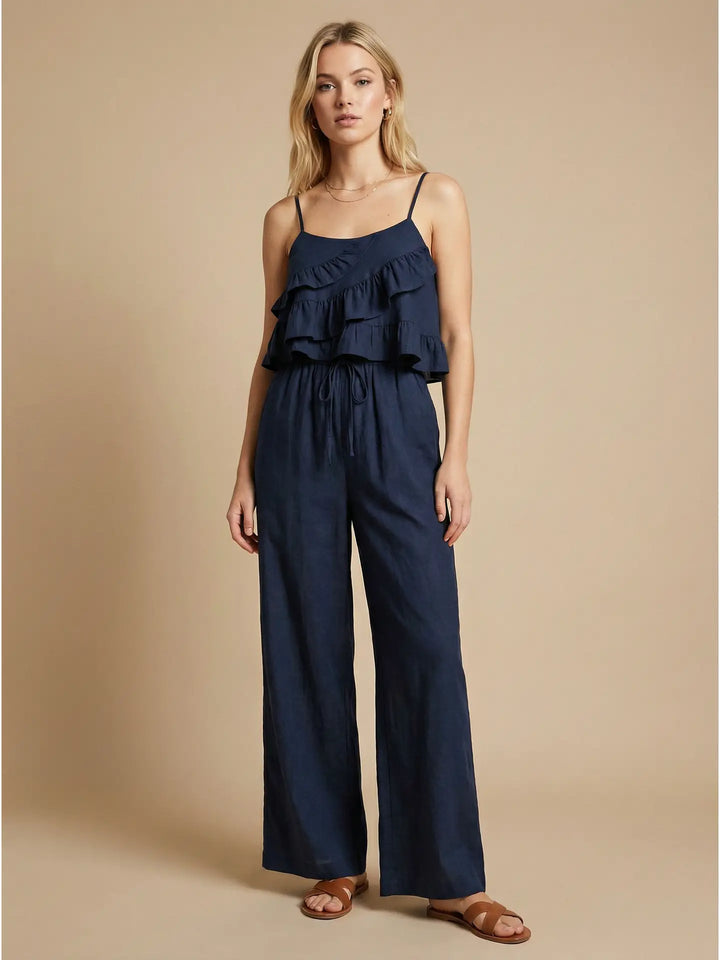 Woman wearing a navy blue jumpsuit with ruffled top on a beige background