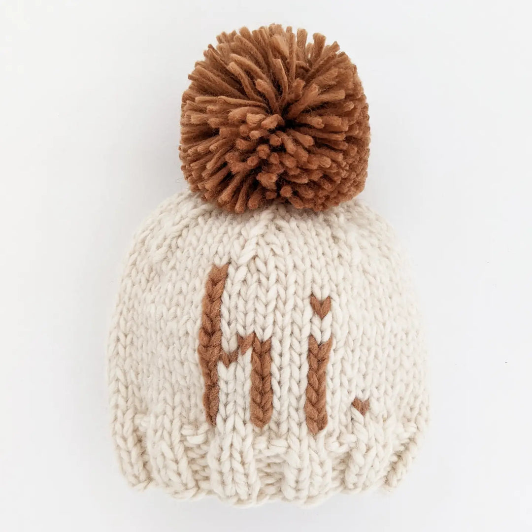 Natural hand-knit Hi There Baby Hat with pecan hi. lettering and pecan pom pom