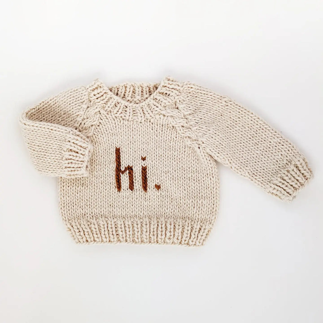 Natural hand-knit Hi There Baby Sweater with pecan hi. lettering and cable raglan sleeves