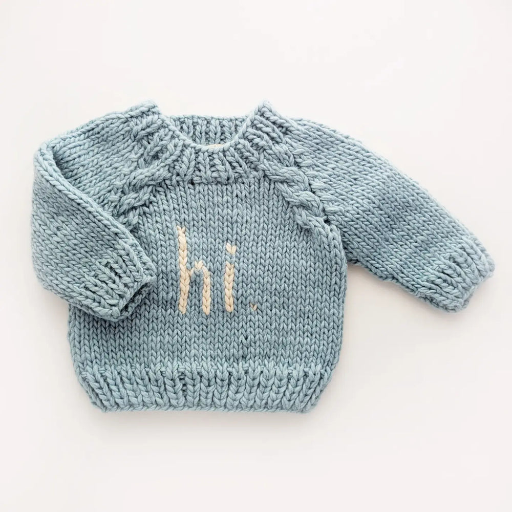 Surf blue hand-knit Hi There Baby Sweater with natural hi. lettering and cable raglan sleeves