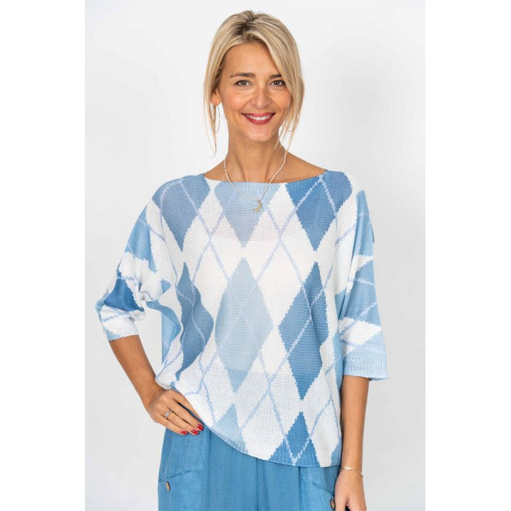 Woman wearing a blue and white argyle sweater against a white background