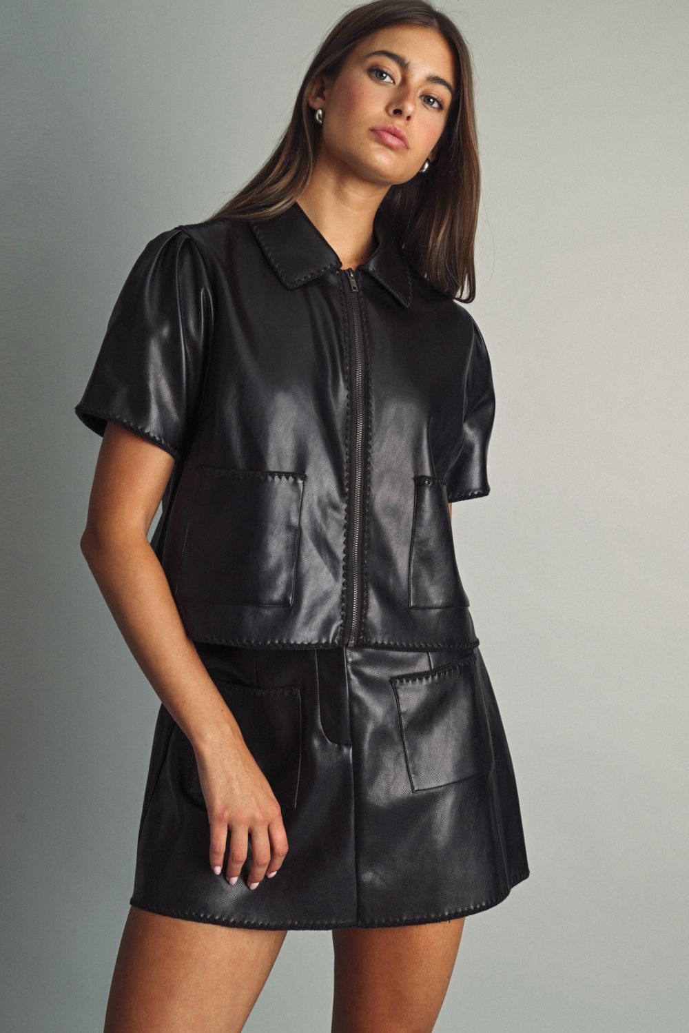 Rhodes Faux Leather Mini Skirt in black, three-quarter view styled with the matching Rhodes Faux Leather Zip Top