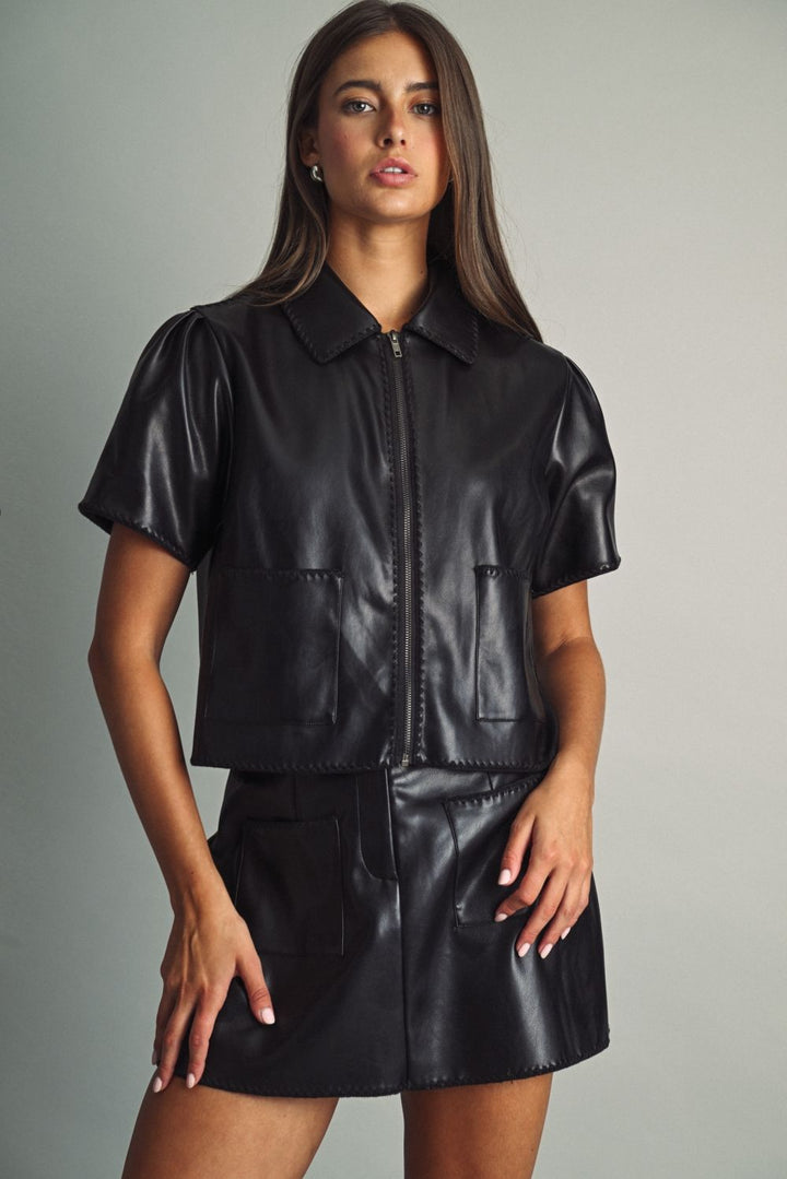 Rhodes Faux Leather Zip Top in black, front view styled with a faux leather mini skirt