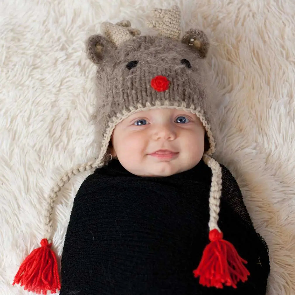Swaddled baby wearing the Rudolph Baby Hat with red tassel ties