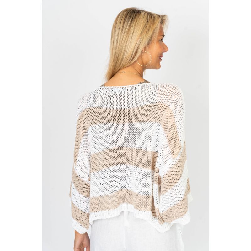 Woman wearing a beige and white striped sweater on a plain background