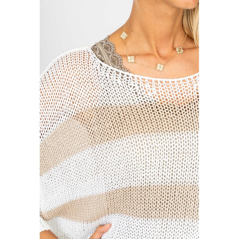 Woman wearing a beige and white mesh top with a plain background