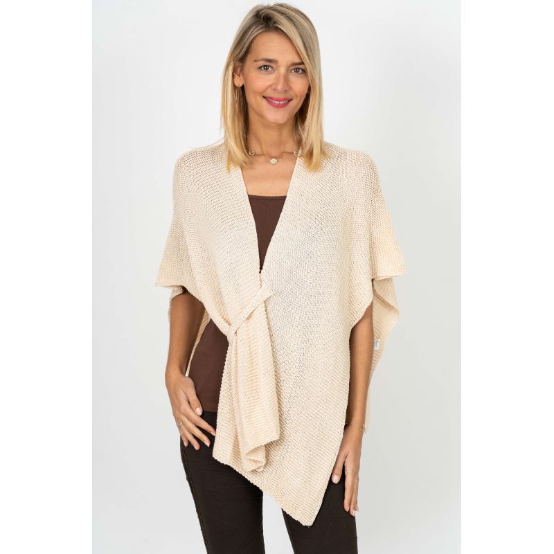 Woman wearing a beige knitted poncho on a white background