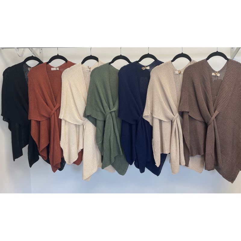 Row of cardigans in various colors on hangers against a white wall.