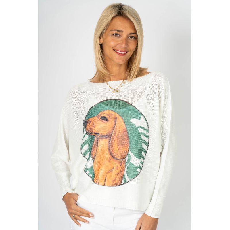 Woman wearing a white sweater with a dachshund design on a plain background