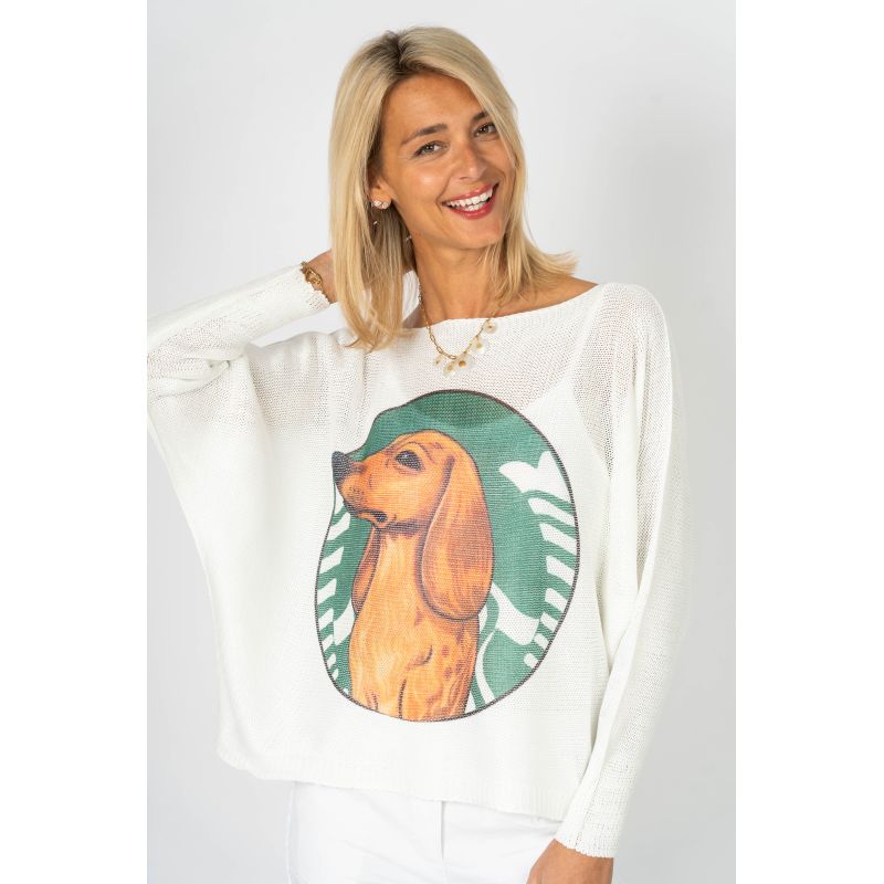 Woman wearing a white sweater with a dog graphic on a plain background