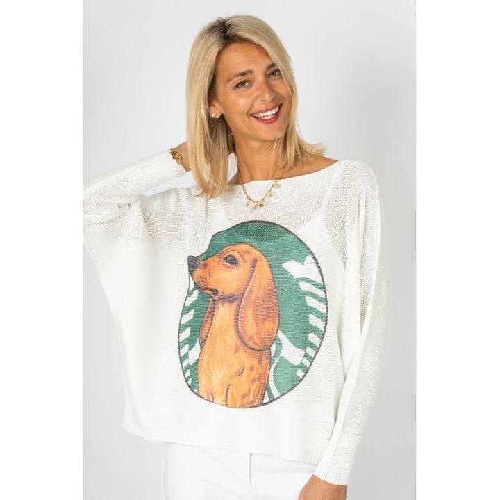 Woman wearing a white sweater with a dog graphic on a plain background