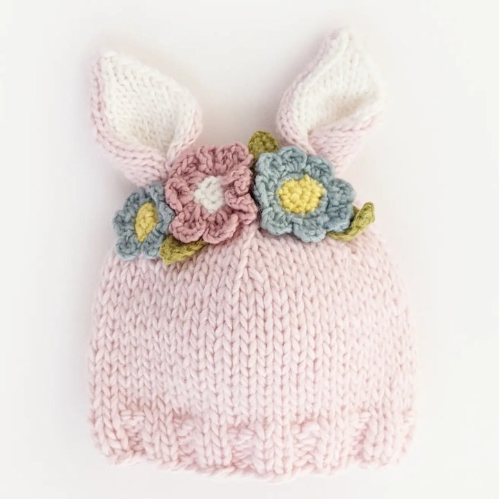 Blush hand-knit Wildflower Bunny Baby Hat with cream-lined bunny ears and a multicolor flower garland